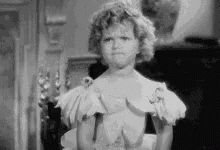 A Black And White Photo Of A Little Girl In A White Dress Making A Funny Face . GIF