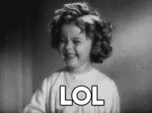 A Black And White Photo Of A Little Girl Laughing With The Word Lol Written On Her Face . GIF