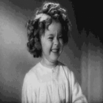 A Black And White Photo Of A Little Girl Smiling In A Room . GIF