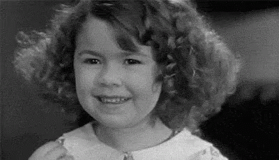 A Black And White Photo Of A Little Girl Smiling . GIF