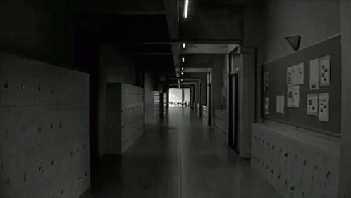 A Black And White Photo Of A Long Hallway In A School With Lockers And A Bulletin Board . GIF