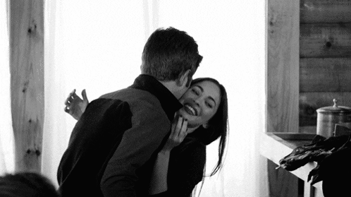 A Black And White Photo Of A Man And A Woman Hugging Each Other . GIF