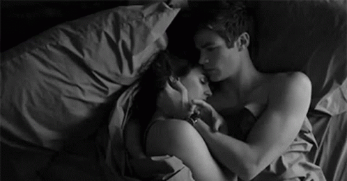 A Black And White Photo Of A Man And A Woman Hugging Each Other In Bed . GIF