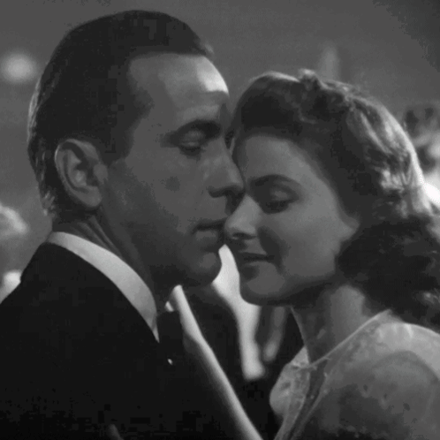 a black and white photo of a man and a woman kissing