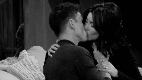 A Black And White Photo Of A Man And A Woman Kissing On A Couch . GIF