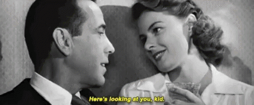 a black and white photo of a man and a woman looking at each other .