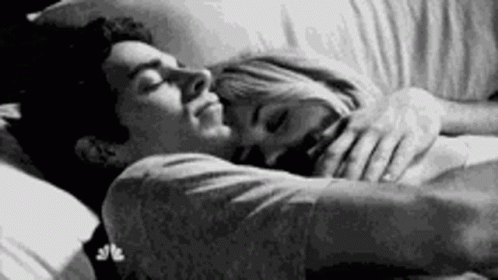 A Black And White Photo Of A Man And A Woman Sleeping In Bed . GIF