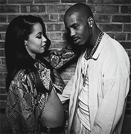 A Black And White Photo Of A Man And A Woman Standing Next To Each Other GIF