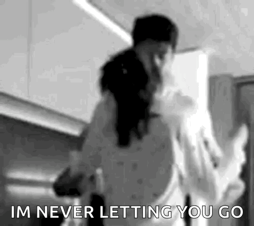 A Black And White Photo Of A Man And Woman Dancing In A Kitchen With The Words `` Im Never Letting You Go '' . GIF