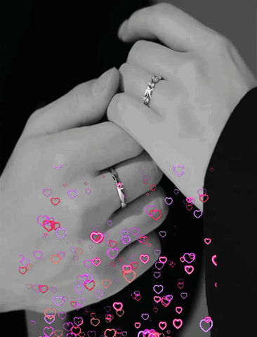 A Black And White Photo Of A Man And Woman Holding Hands With Hearts Flying Around Them GIF
