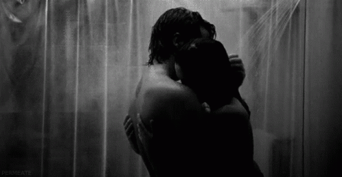 A Black And White Photo Of A Man And Woman Hugging Under A Shower Curtain . GIF