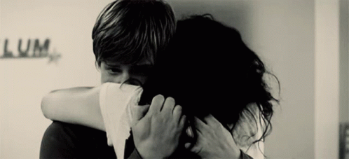 A Black And White Photo Of A Man And Woman Hugging With The Word Lum Written On The Wall Behind Them GIF