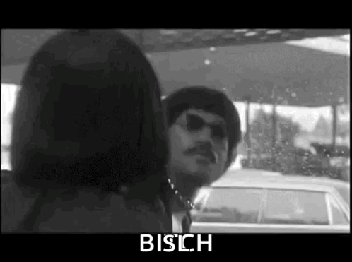 A Black And White Photo Of A Man And Woman In A Car . GIF
