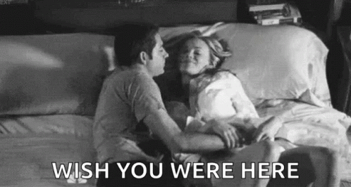 A Black And White Photo Of A Man And Woman Kissing On A Bed With The Words `` Wish You Were Here '' . GIF