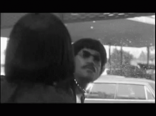 A Black And White Photo Of A Man And Woman Looking At Each Other GIF
