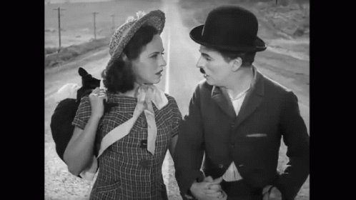 A Black And White Photo Of A Man And Woman Standing Next To Each Other GIF