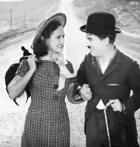 A Black And White Photo Of A Man And Woman Standing Next To Each Other GIF