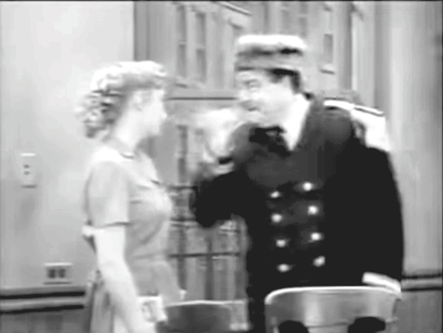 A Black And White Photo Of A Man And Woman Talking To Each Other GIF