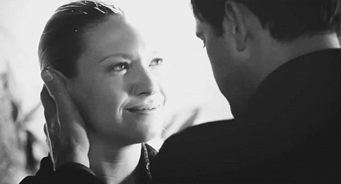 A Black And White Photo Of A Man And Woman Touching Each Other 'S Faces . GIF