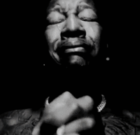 A Black And White Photo Of A Man Covering His Mouth With His Hands GIF