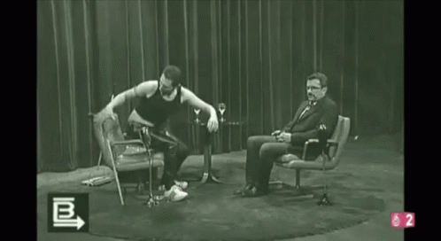 A Black And White Photo Of A Man Dancing In Front Of A Man Sitting In A Chair With The Number 2 On The Bottom GIF