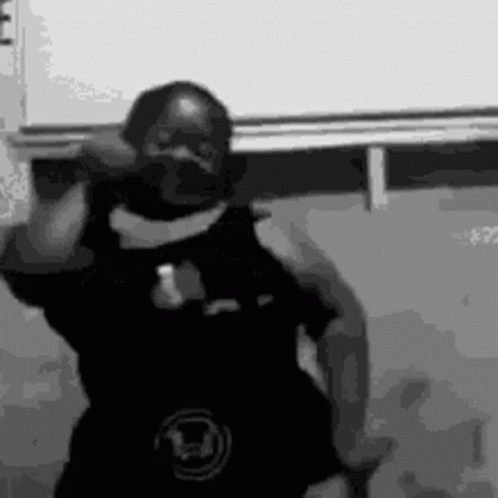 A Black And White Photo Of A Man Dancing In Front Of A White Wall . GIF