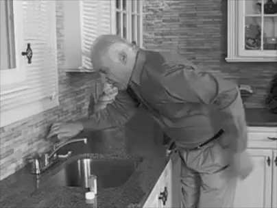 A Black And White Photo Of A Man Fixing A Sink Faucet In A Kitchen . GIF