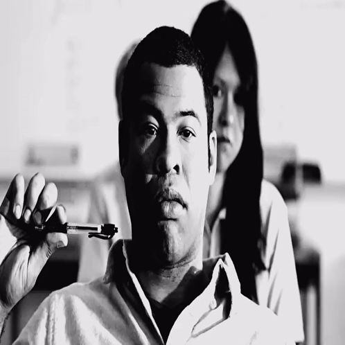 A Black And White Photo Of A Man Holding A Pen In His Hand GIF
