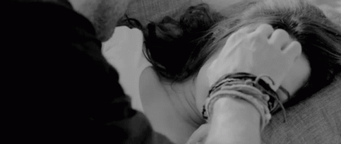 A Black And White Photo Of A Man Holding A Woman 'S Hand While Laying On A Bed . GIF