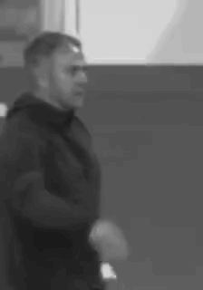 A Black And White Photo Of A Man In A Black Jacket Standing In A Room . GIF
