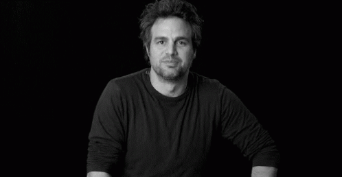 A Black And White Photo Of A Man In A Black Shirt Smiling . GIF