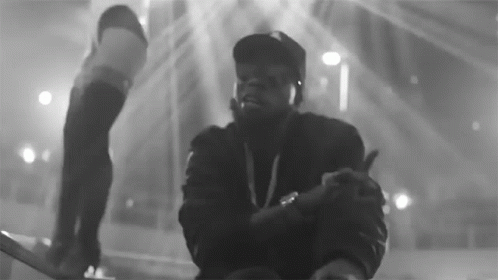 A Black And White Photo Of A Man In A Hat Giving A Thumbs Up GIF
