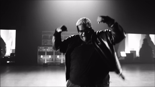 A Black And White Photo Of A Man In A Jacket Dancing GIF