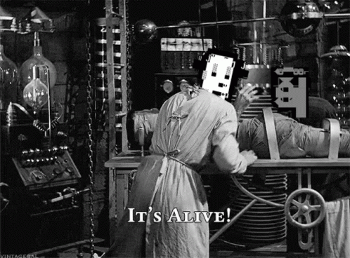 A Black And White Photo Of A Man In A Lab With The Words `` It 'S Alive '' On The Bottom . GIF
