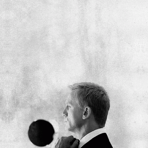 A Black And White Photo Of A Man In A Suit Adjusting His Tie GIF