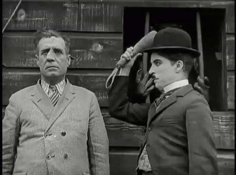 A Black And White Photo Of A Man In A Suit And A Man In A Bowler Hat GIF
