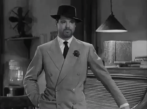 A Black And White Photo Of A Man In A Suit And Hat GIF