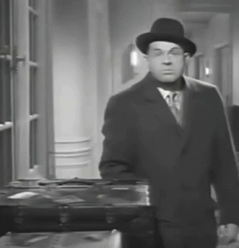 A Black And White Photo Of A Man In A Suit And Hat GIF
