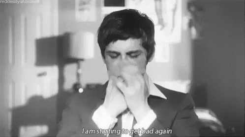 A Black And White Photo Of A Man In A Suit And Tie Covering His Mouth . GIF