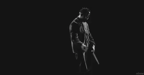 A Black And White Photo Of A Man In A Suit And Tie Dancing In The Dark . GIF