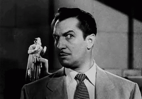 A Black And White Photo Of A Man In A Suit And Tie Holding A Statue . GIF