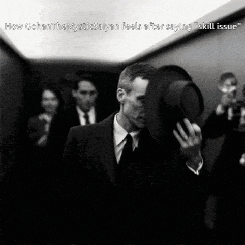 A Black And White Photo Of A Man In A Suit And Tie Holding His Hat GIF