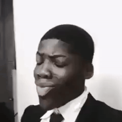 A Black And White Photo Of A Man In A Suit And Tie Making A Face . GIF