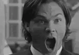 A Black And White Photo Of A Man In A Suit And Tie With His Mouth Open . GIF