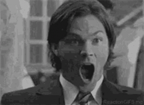 A Black And White Photo Of A Man In A Suit And Tie With His Mouth Wide Open . GIF