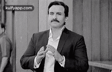 A Black And White Photo Of A Man In A Suit Clapping His Hands . GIF