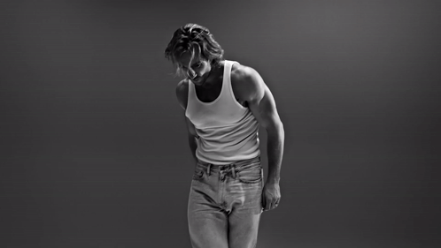 A Black And White Photo Of A Man In A Tank Top And Jeans GIF