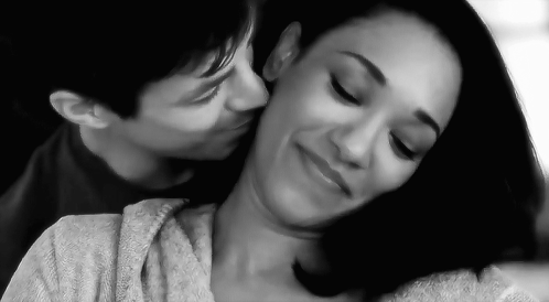 A Black And White Photo Of A Man Kissing A Woman On The Cheek . GIF