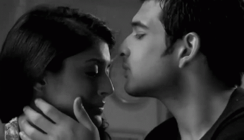A Black And White Photo Of A Man Kissing A Woman On The Cheek . GIF