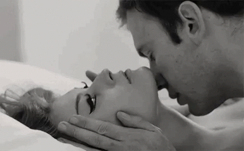 A Black And White Photo Of A Man Kissing A Woman On The Forehead . GIF
